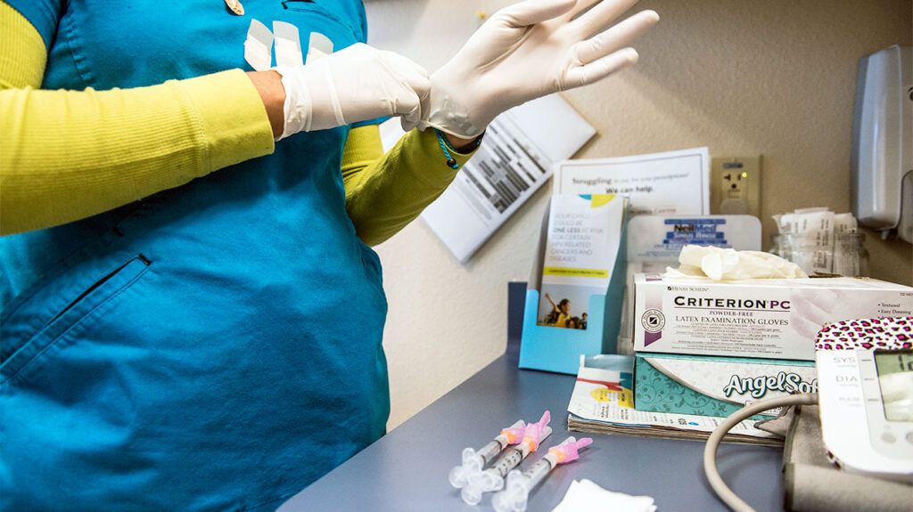 A healthcare professional putting on latex gloves 1