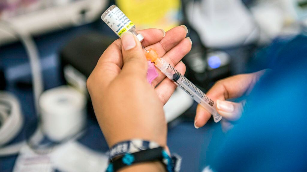 A person preparing a syringe with HPV vaccine 1