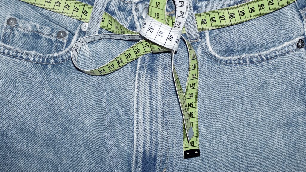 a tape measure is looped around a pair of blue jeans