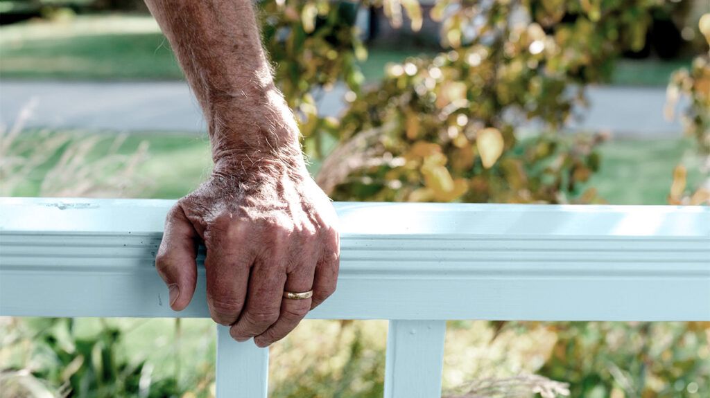 A person's hand resting on a banister