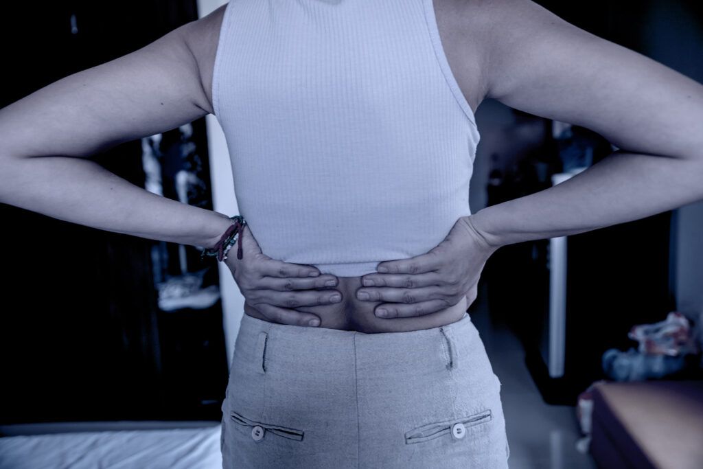 Female touching her lower back with both hands