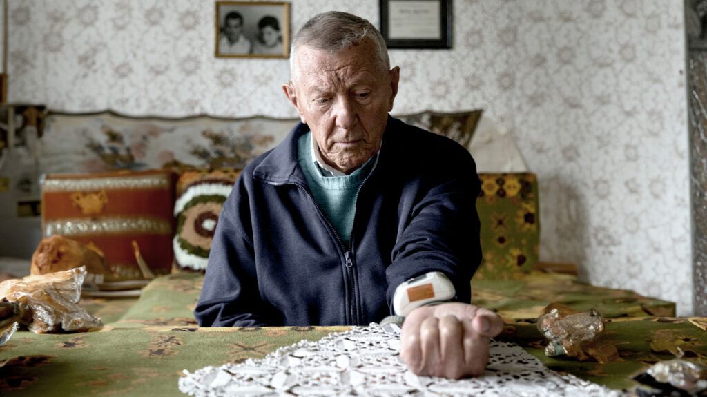 Un uomo anziano controlla la pressione sanguigna utilizzando un dispositivo di monitoraggio domestico