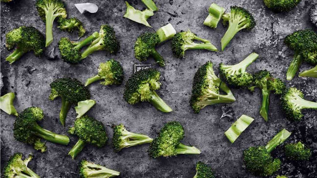 broccoli pieces are spread over a gray tray