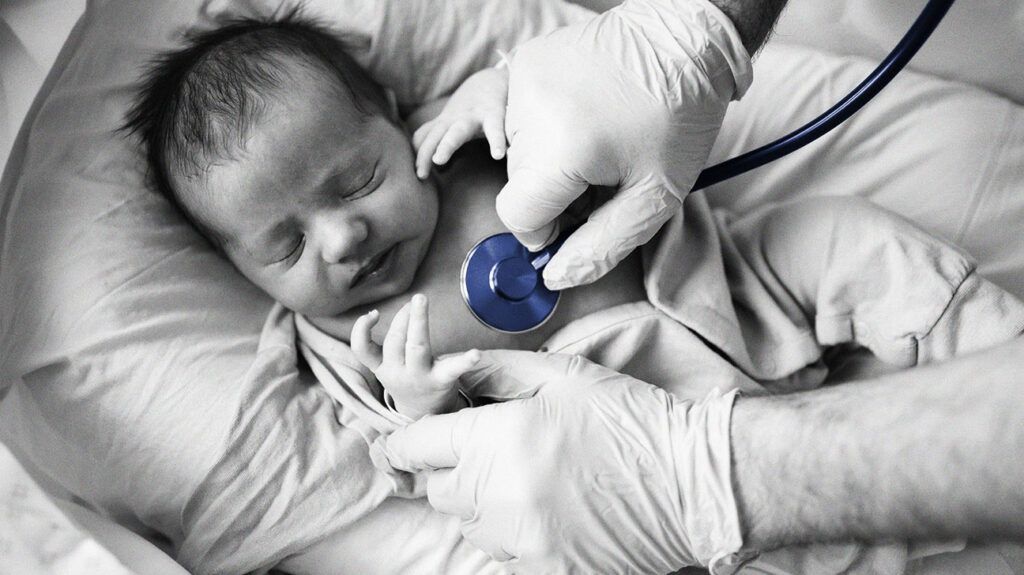 Closeup of a medical professional using a stethoscope on a baby.