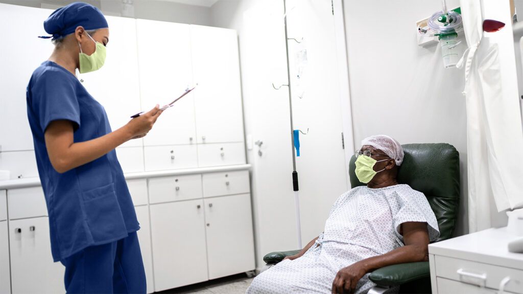 A healthcare professional speaking with a person in a hospital gown 1