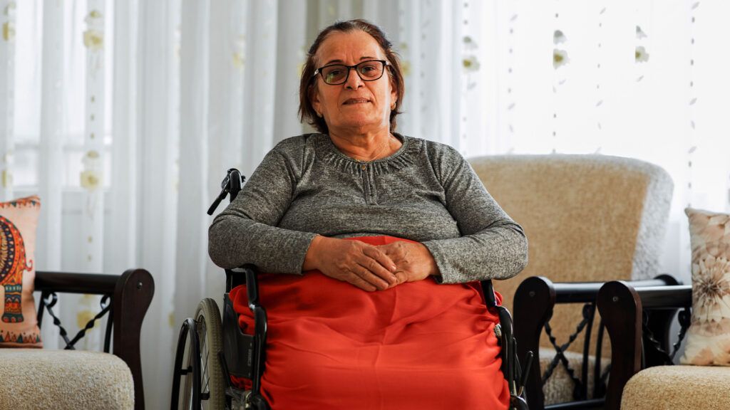 Una donna anziana è seduta su una sedia a rotelle con una coperta in grembo
