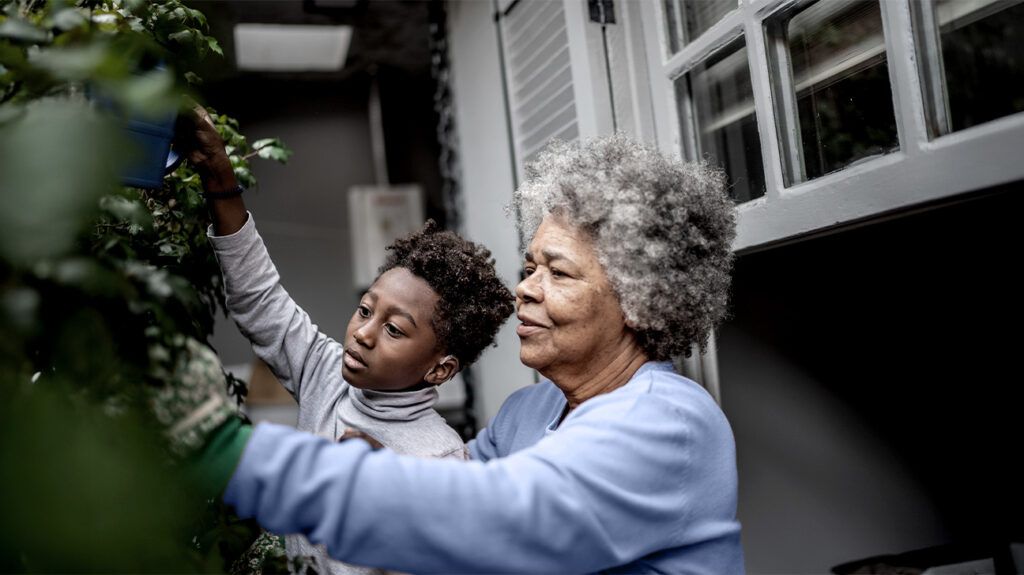 A grandmother and child gardening outside the house