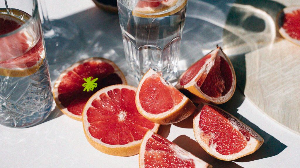 Slices of grapefruit next to a glass of water