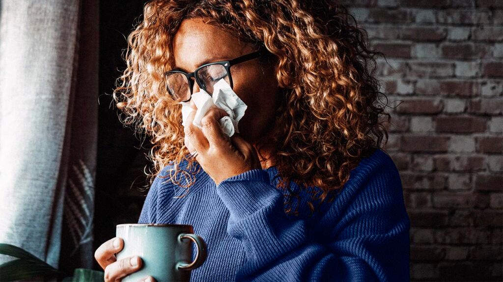 a woman is sneezing into a paper towel