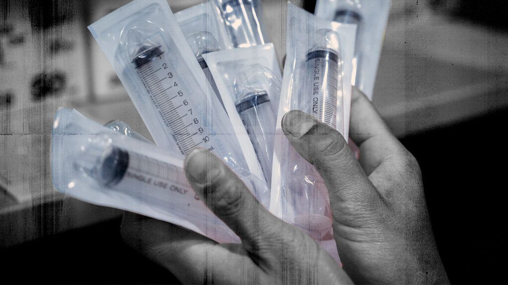 Close-up of a health worker holding sealed syringes of injectable medications for PsA.