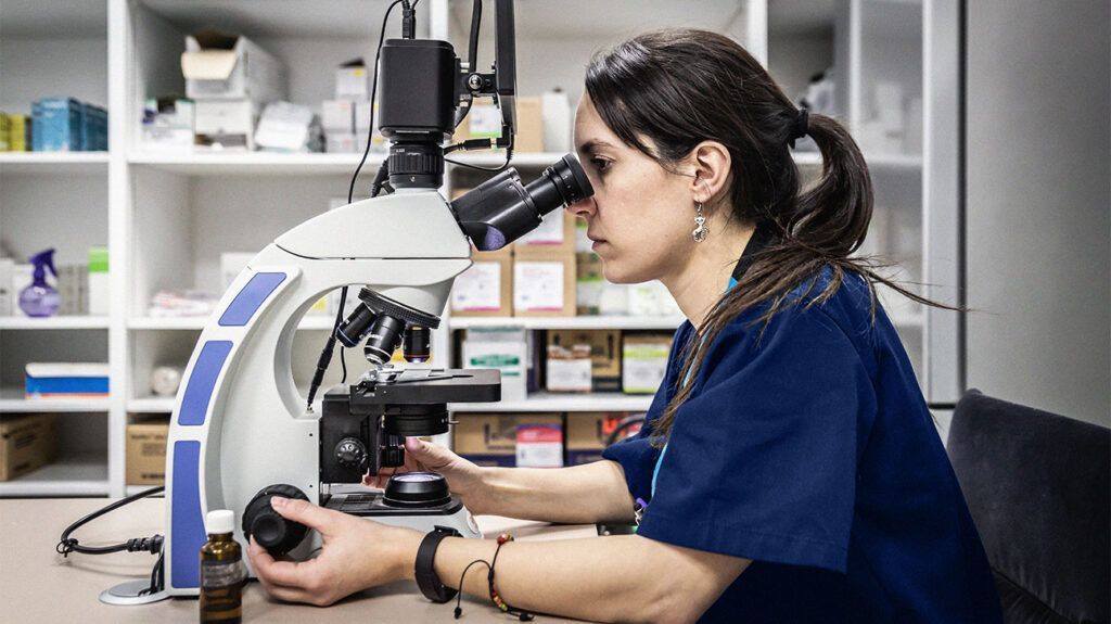 A healthcare professional looking into a microscope 1
