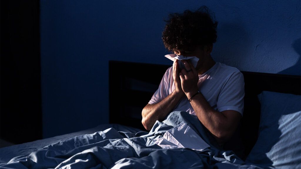 A man blowing his nose at night due to allergies -1.