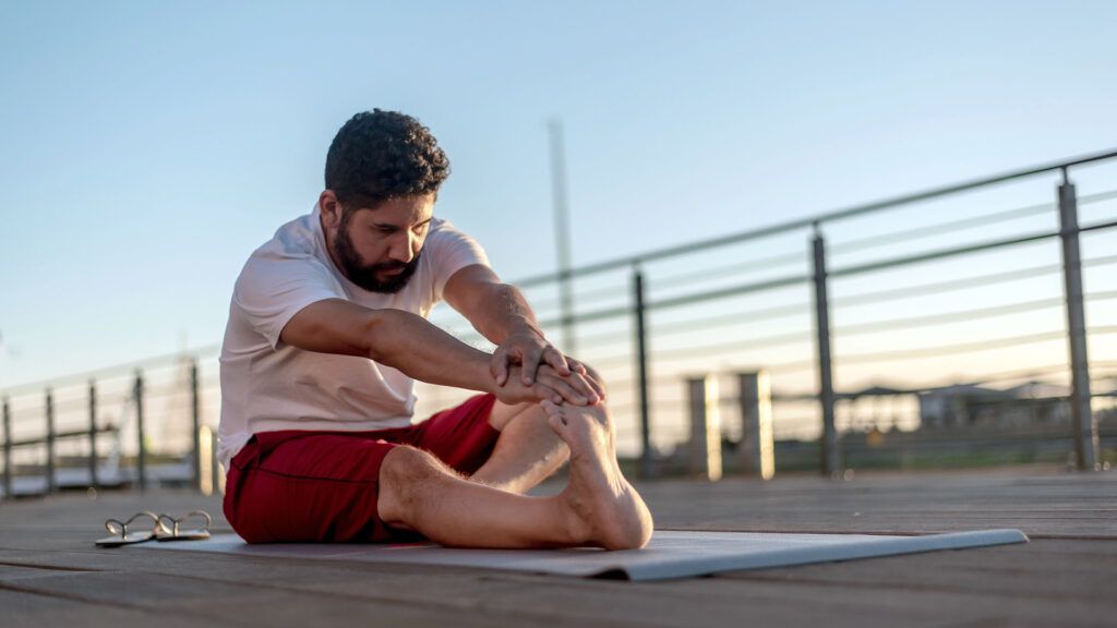 man with a beard stretching on rooftop