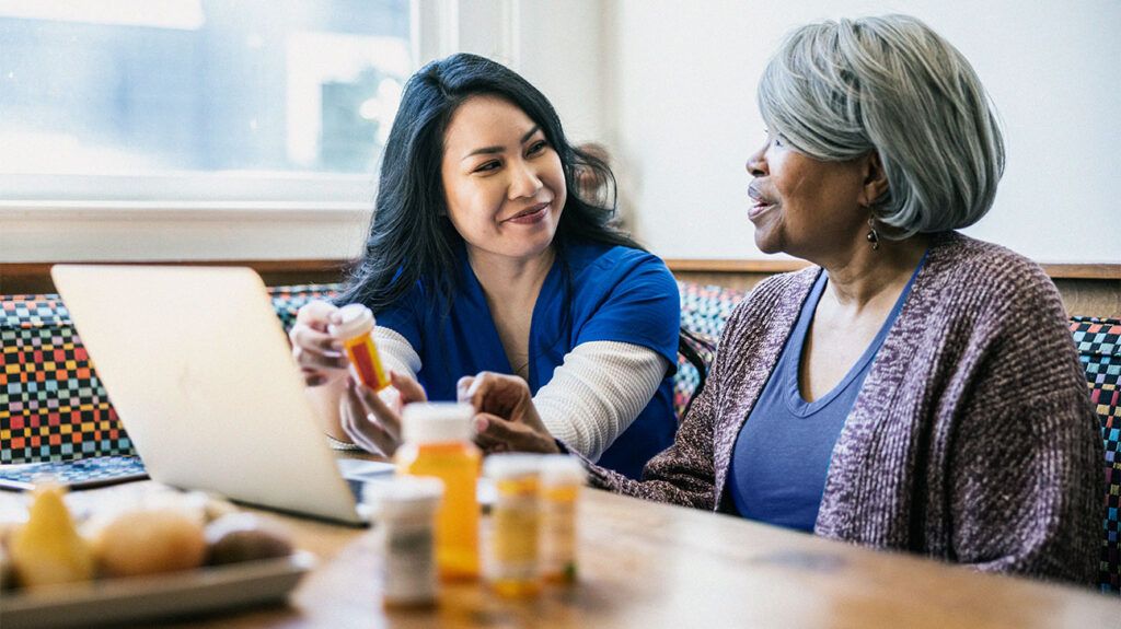 A healthcare professional showing medication to an older woman-1