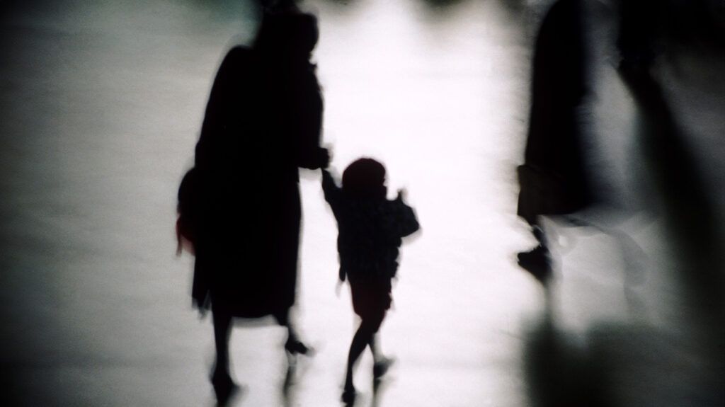 Silhouette of a parent and small child holding hands