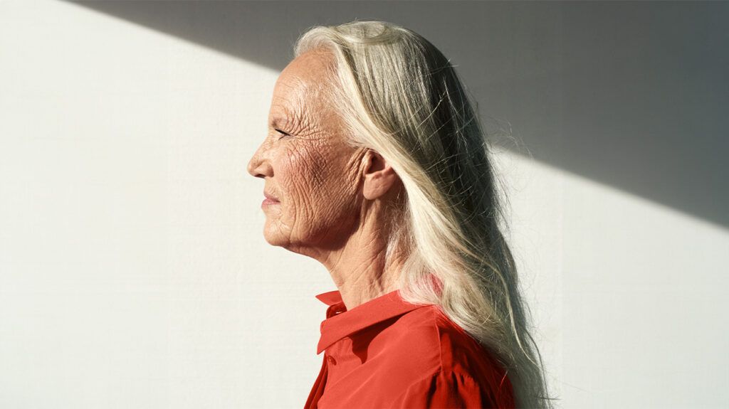 An older woman with blond hair stares straight ahead