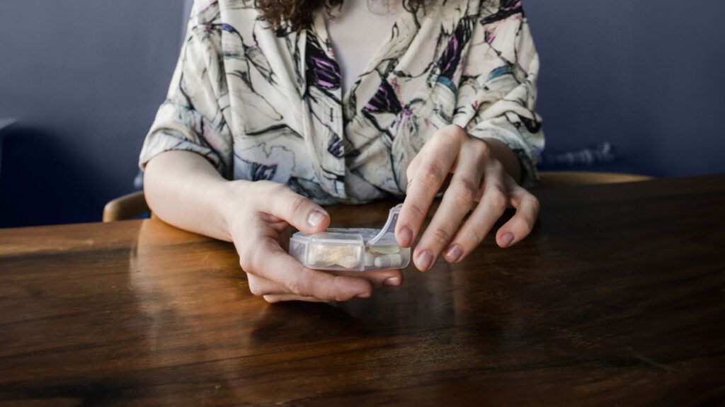 A person is holding a pill box.