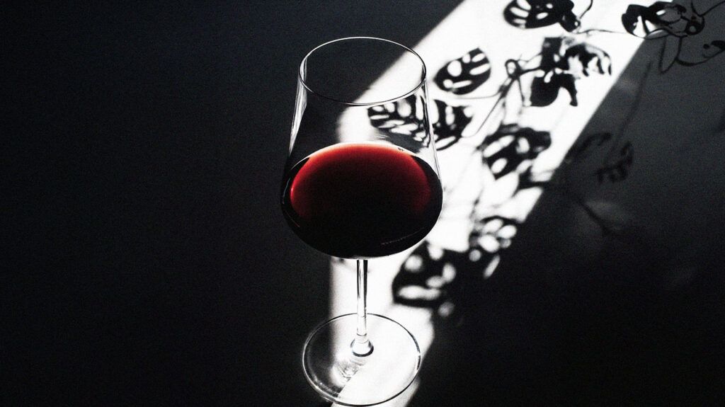 A beam of sunlight shines on a glass of red wine