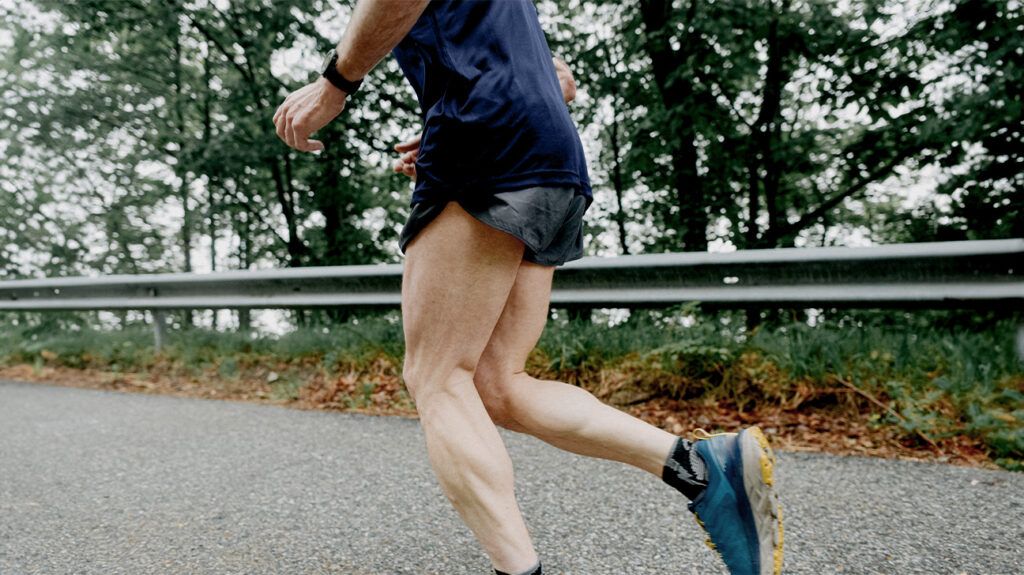 A man in running shorts jogs along a road