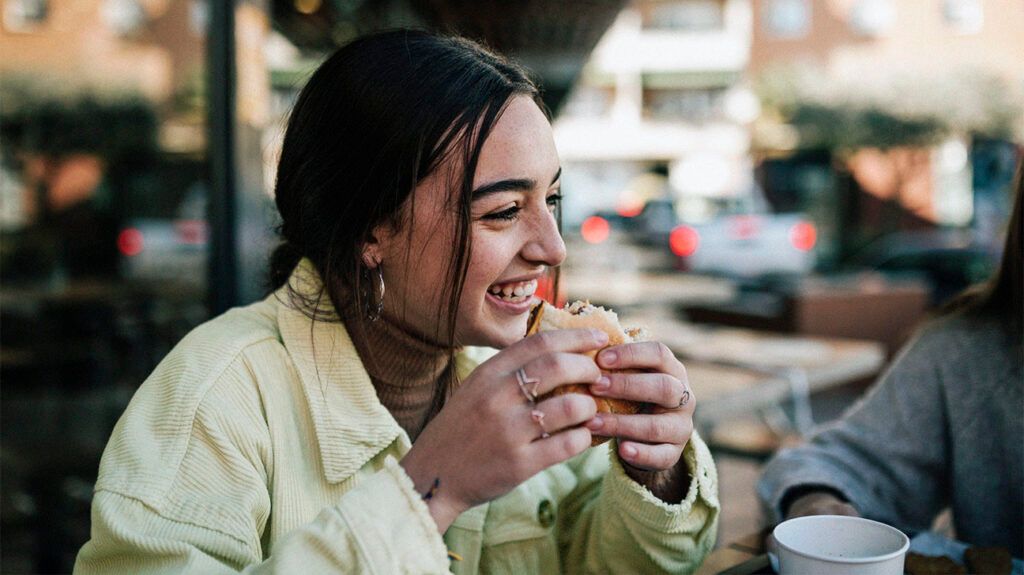 A person smiling and holding a burger 1