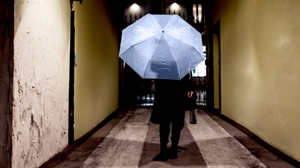 Person walking down a hallway with an open umbrella