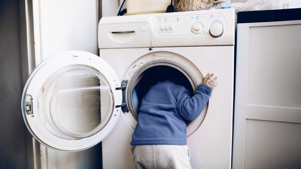 Small child sticking their head in the washing machine