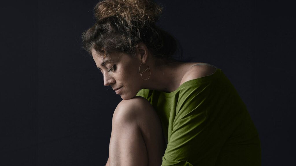 donna in abito verde appoggiato il mento su un ginocchio