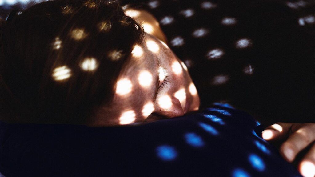 Person lying down with light and shadows on their face