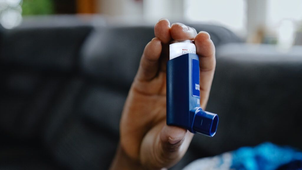 Person holding an asthma inhaler