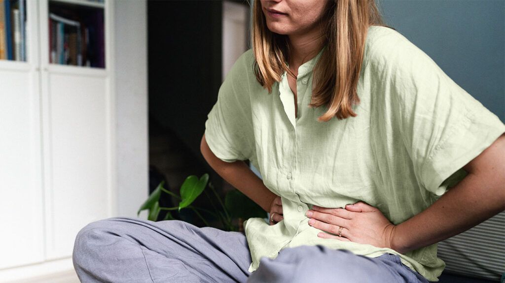 A woman is holding her belly due to stomach pain