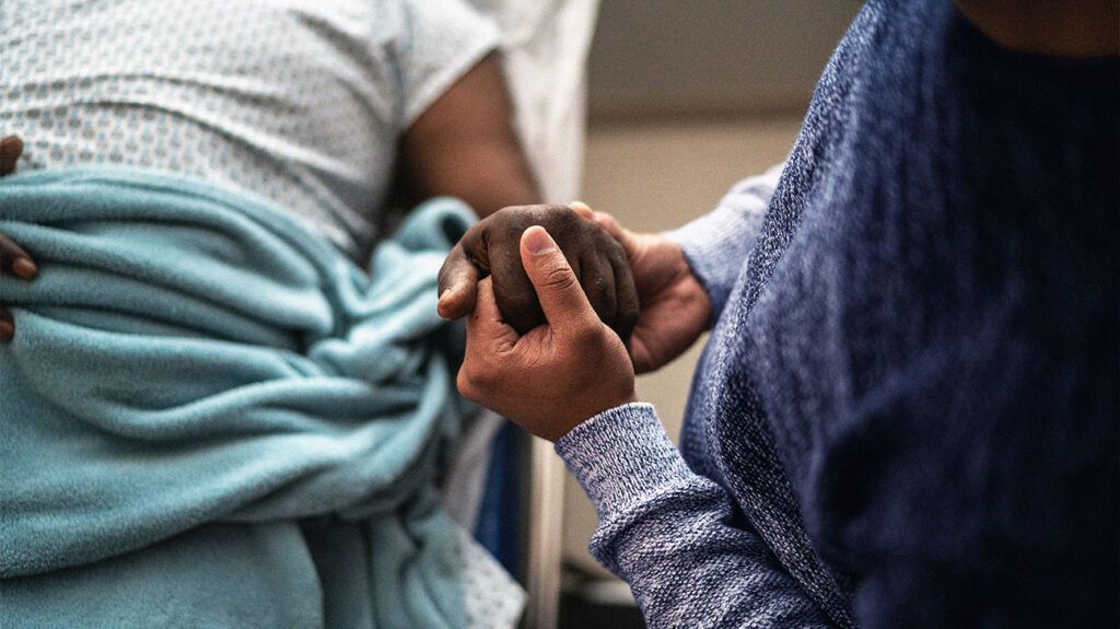 A person holding a patients hand in the hospital. -1