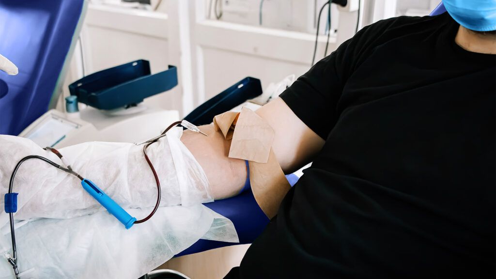 a clinician is drawing blood from a person in hospital