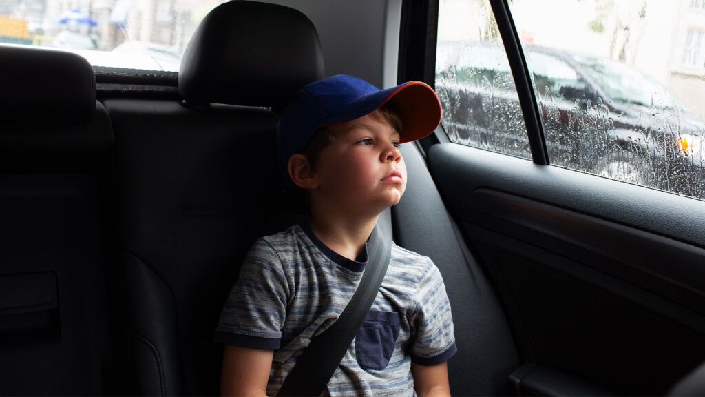 A child with ADHD feeling bored in the back of a car.-1