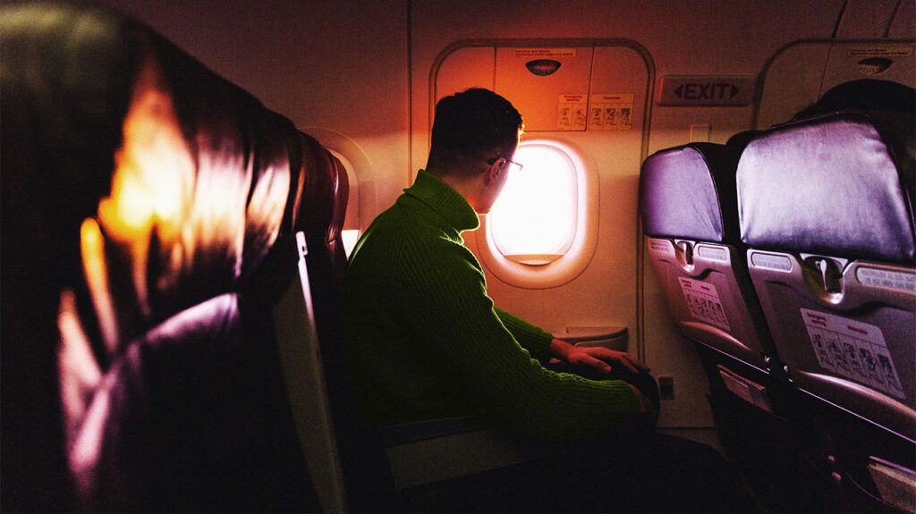 A person on an airplane is looking out of the window.