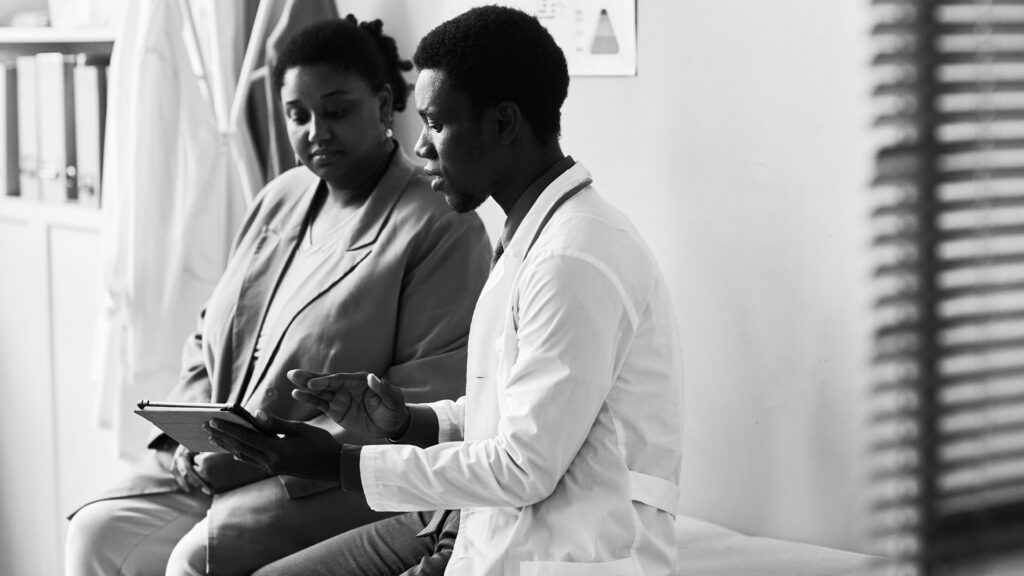 a black and white photo of a doctor talking to a patient
