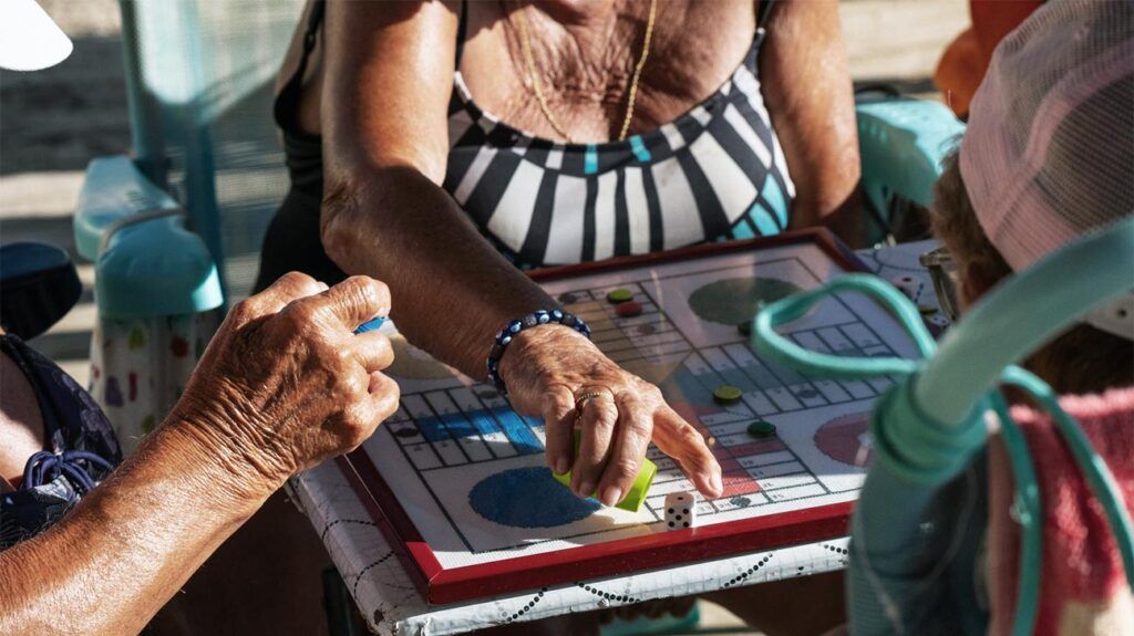 A close up of a group of older adults playing a board game with dice