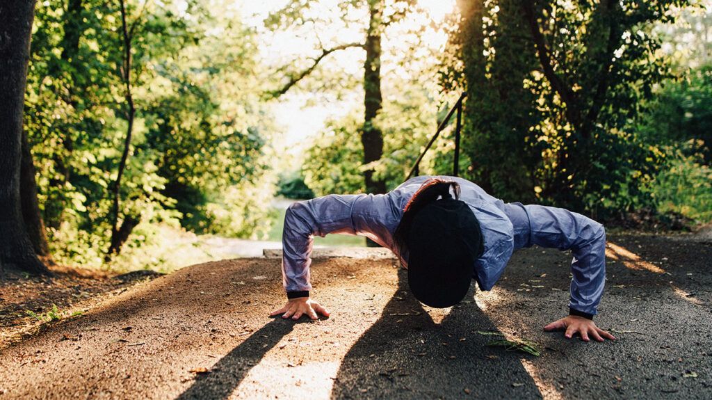 A person with cystic fibrosis doing a push up in a forest.-2