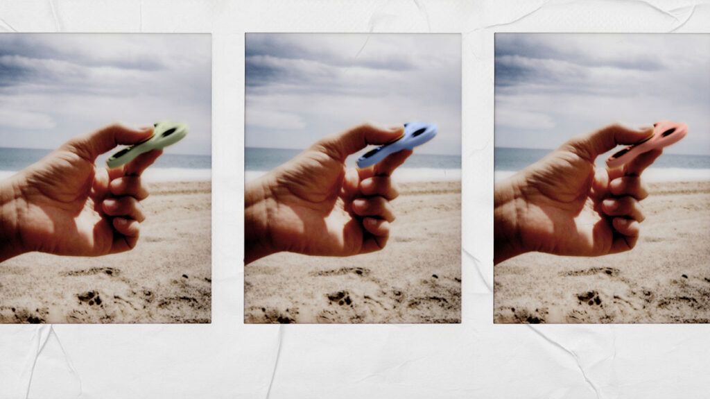 A person with ADHD holding a fidget spinner at a beach.-1