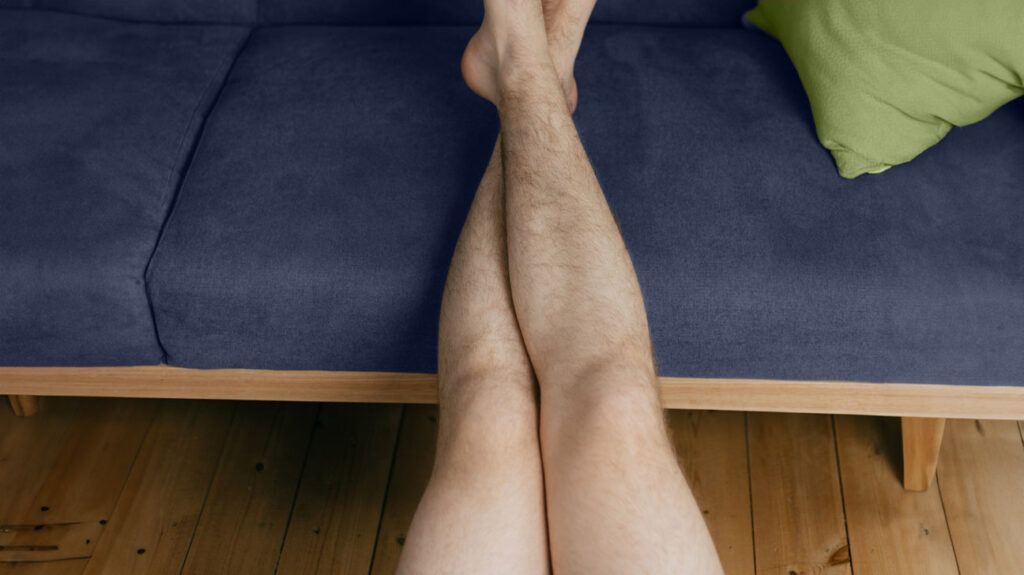 A man rests his legs on a cushion