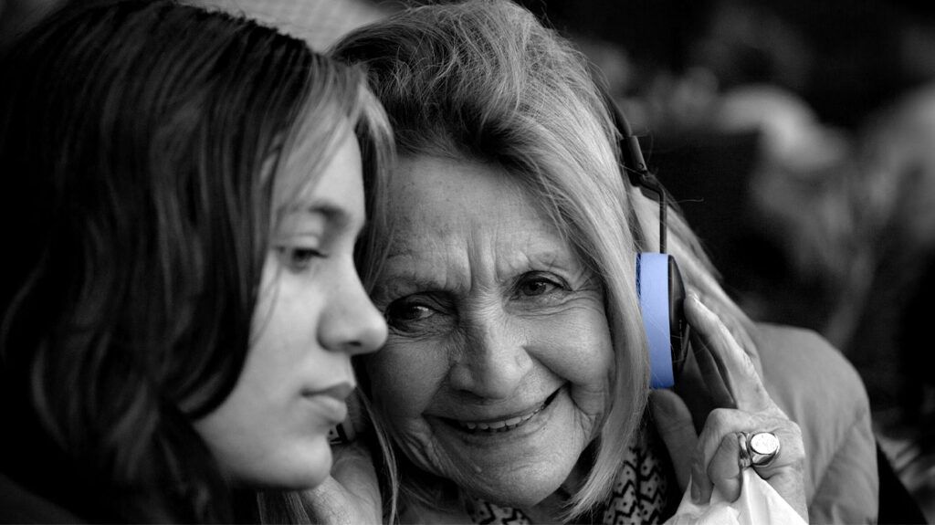 A person with Alzheimer's disease listening to music through headphones with a younger person.-1