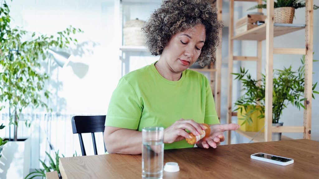 Female sitting at a table taking medication