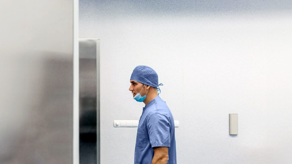Side view of a surgeon walking down a corridor -1.