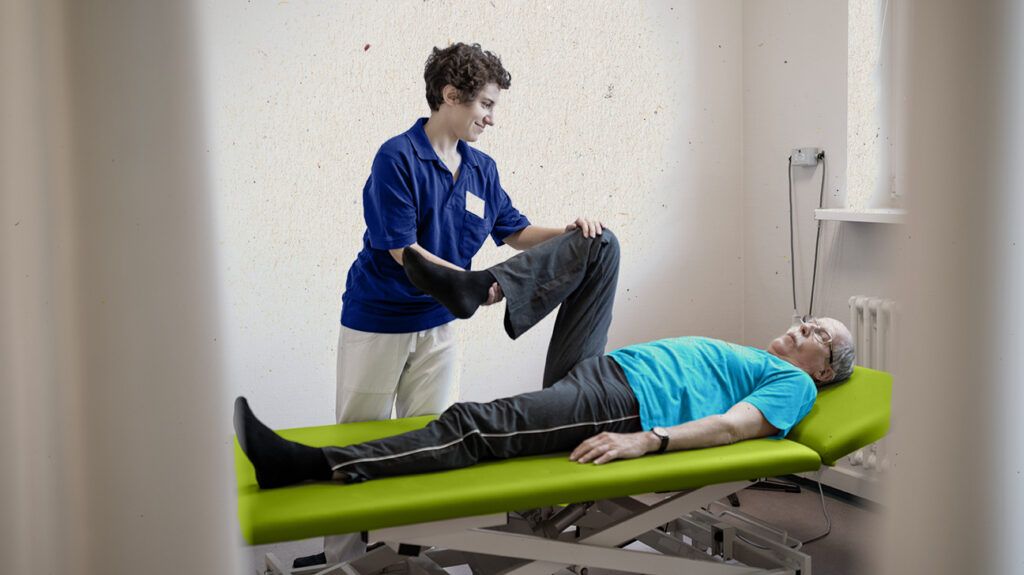 a physiotherapist is moving a person's leg