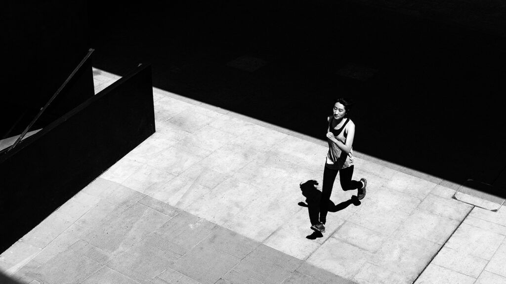 A woman running with a shadow on the ground