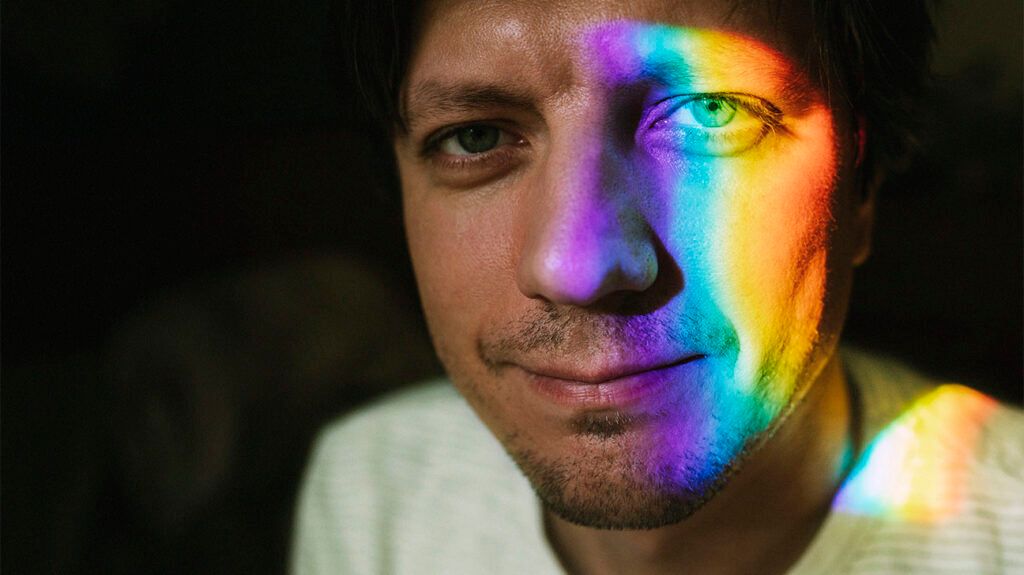 Close up of a male's face with rainbow colored light