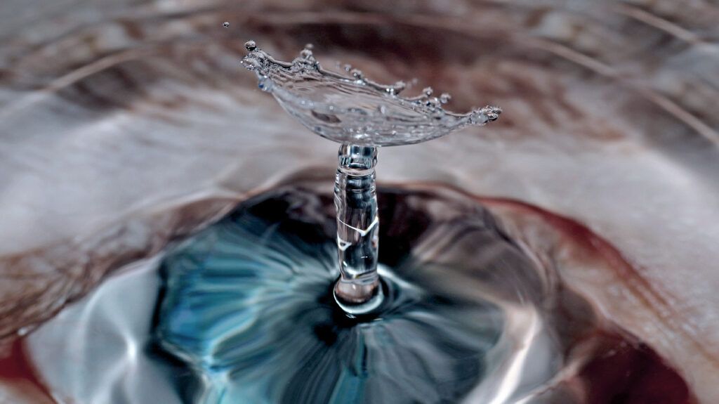 a water drop is falling into the reflection of an eye