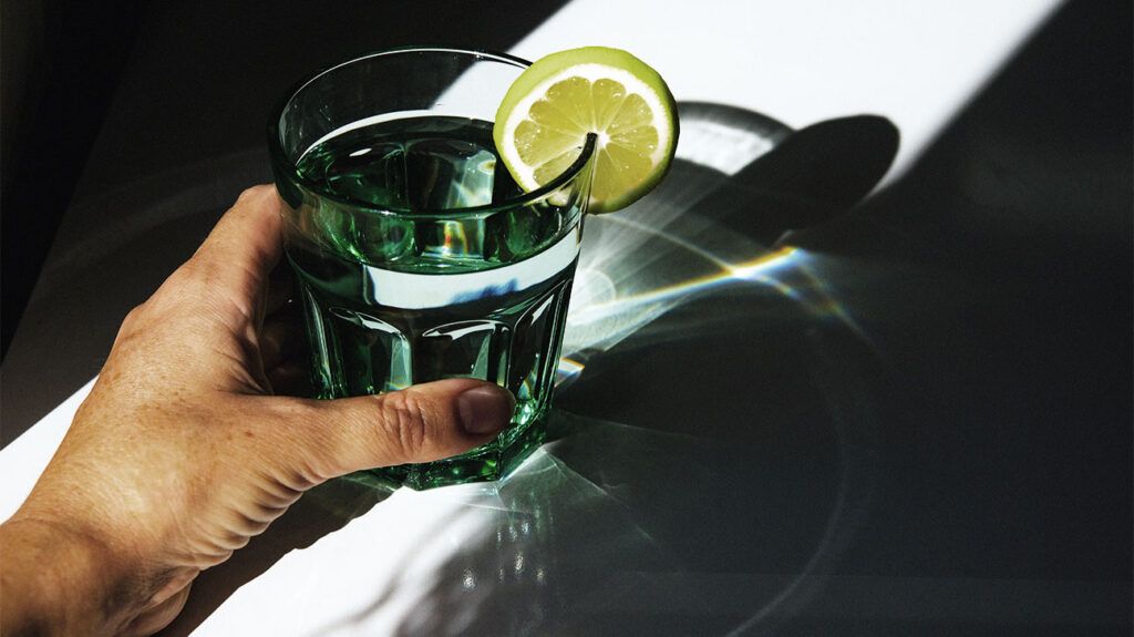 A glass of water with a slice of lemon in the hand of someone with hydrophobia.-1