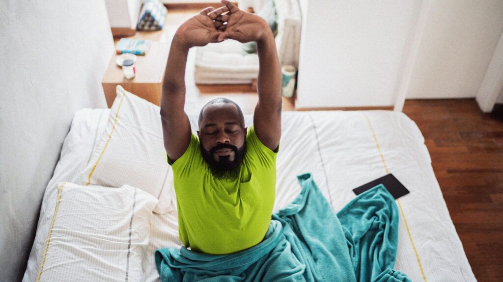 Man waking up and stretching in bed at home