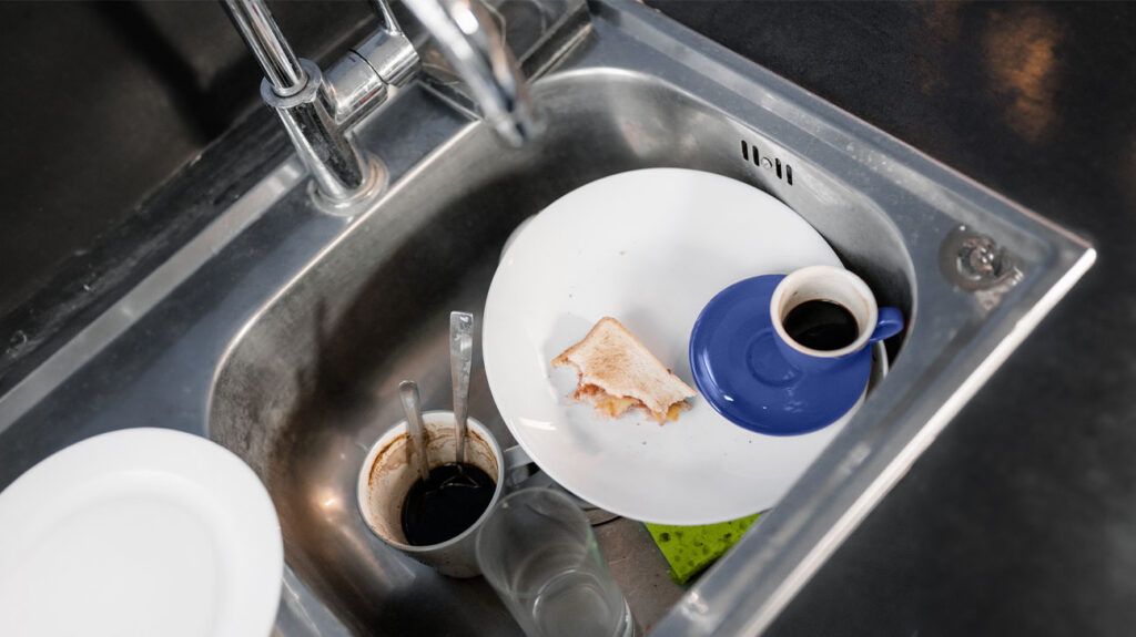 Dirty dishes and coffee cups in a sink.