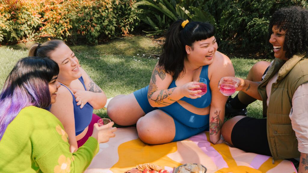 a group of plus sized women in active wear enjoy a picnic outdoor